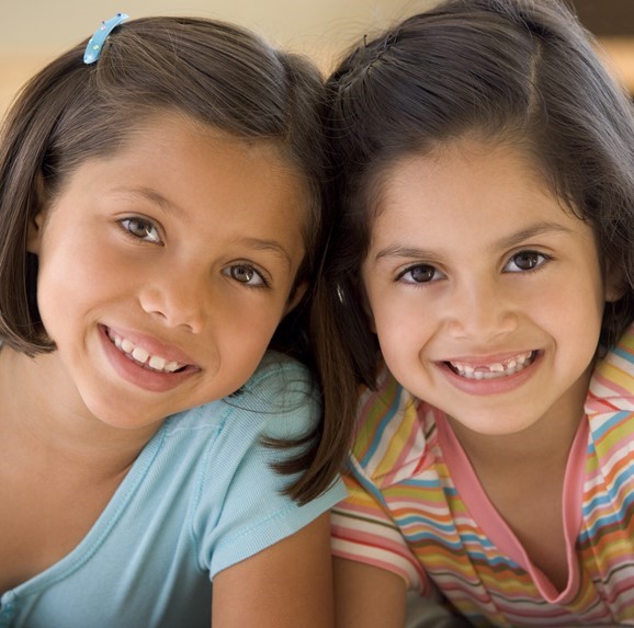Two young Hispanic girls smiling.