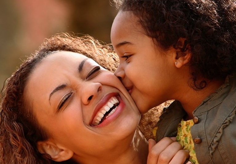 African American mom being kissed on check by daughter