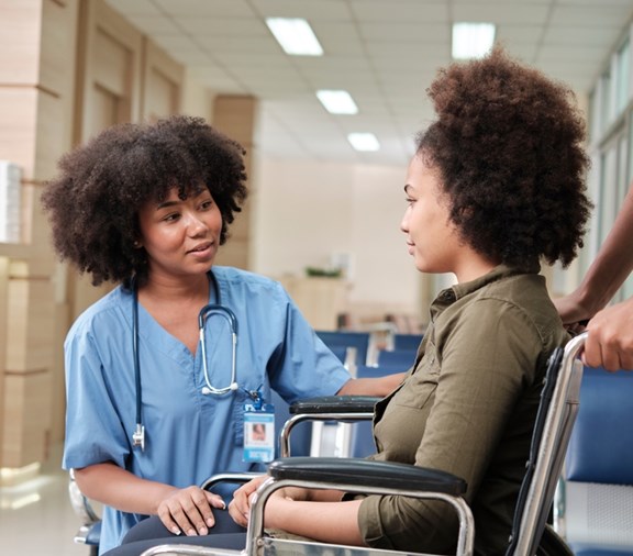 woman leaving hospital in wheelchair with nurse