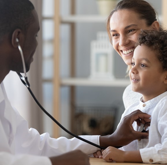 Male doctor attending to child with his mother