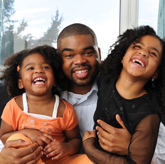 African American father smiling with daughters.