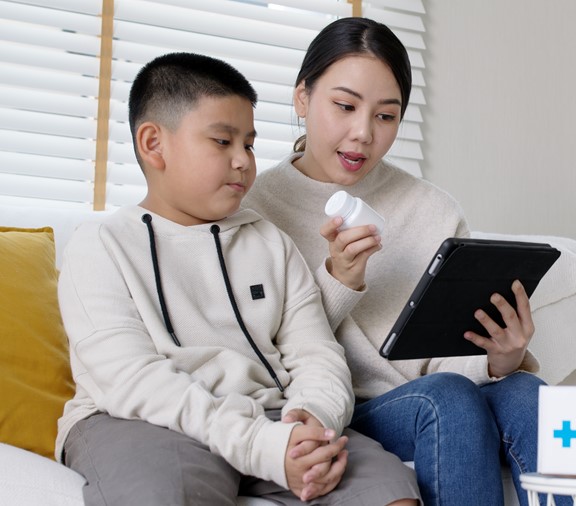 mother helping child with telehealth appointment