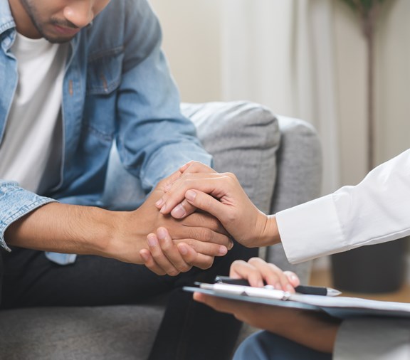 Behavioral health, depression. Sad young man consulting with psychiatrist while patient counseling mental therapy problem with doctor at clinic. Docotr encouraging with sick mental health person
